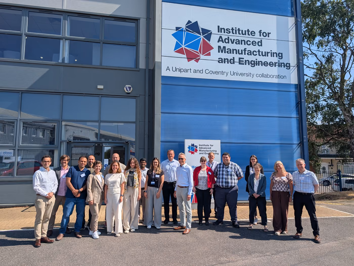 Group of people standing outside the Institute for Advanced Manufacturing and Engineering building.